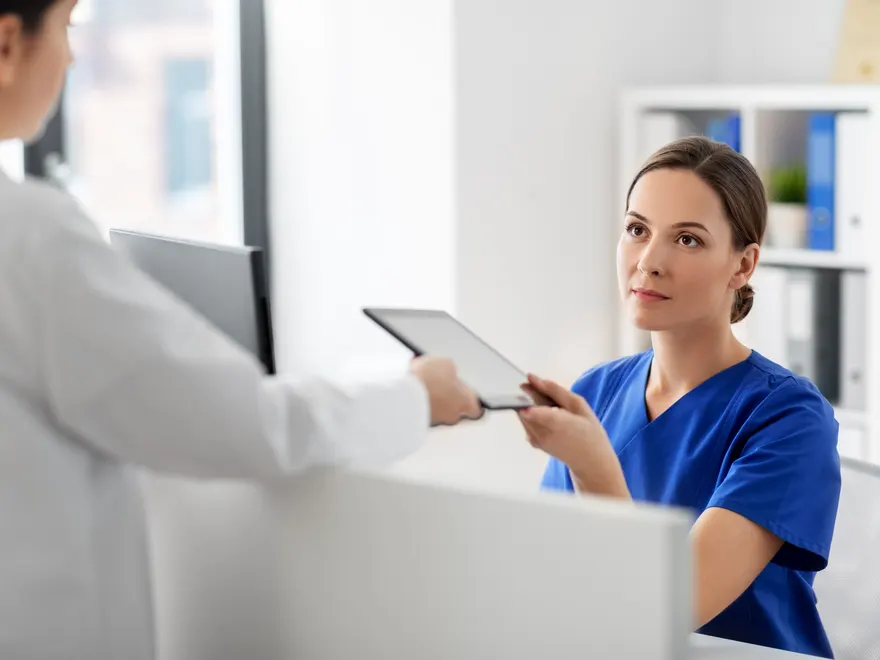 Profesional de clínica usando una tablet para coordinar la atención junto a una colega